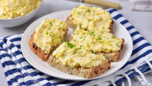 Pyszna pasta jajeczna z twarogiem na chlebie, posypana szczypiorkiem. Idealna na śniadanie lub przekąskę.