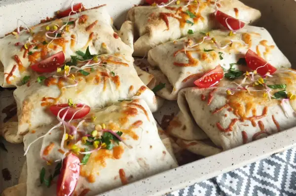 Pyszna tortilla na ciepło z piekarnika, zapieczona z serem, pomidorkami i kiełkami. Idealna na szybki obiad.