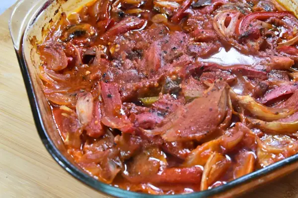 Pyszna karkówka po cygańsku w sosie pomidorowym z cebulą i papryką, zapiekana w szklanym naczyniu.