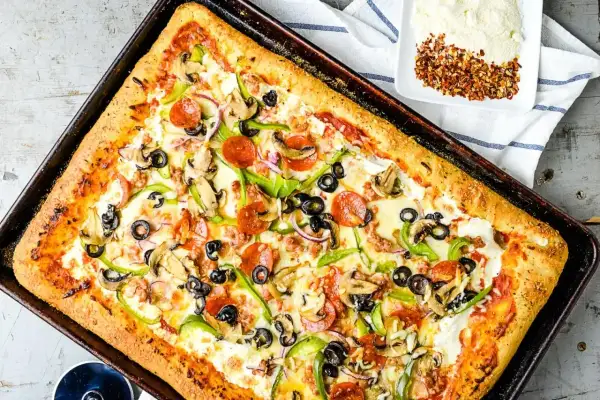 Pyszna pizza domowa na blachę z pieczarkami, papryką, oliwkami i pepperoni. Idealny przepis na szybki obiad.